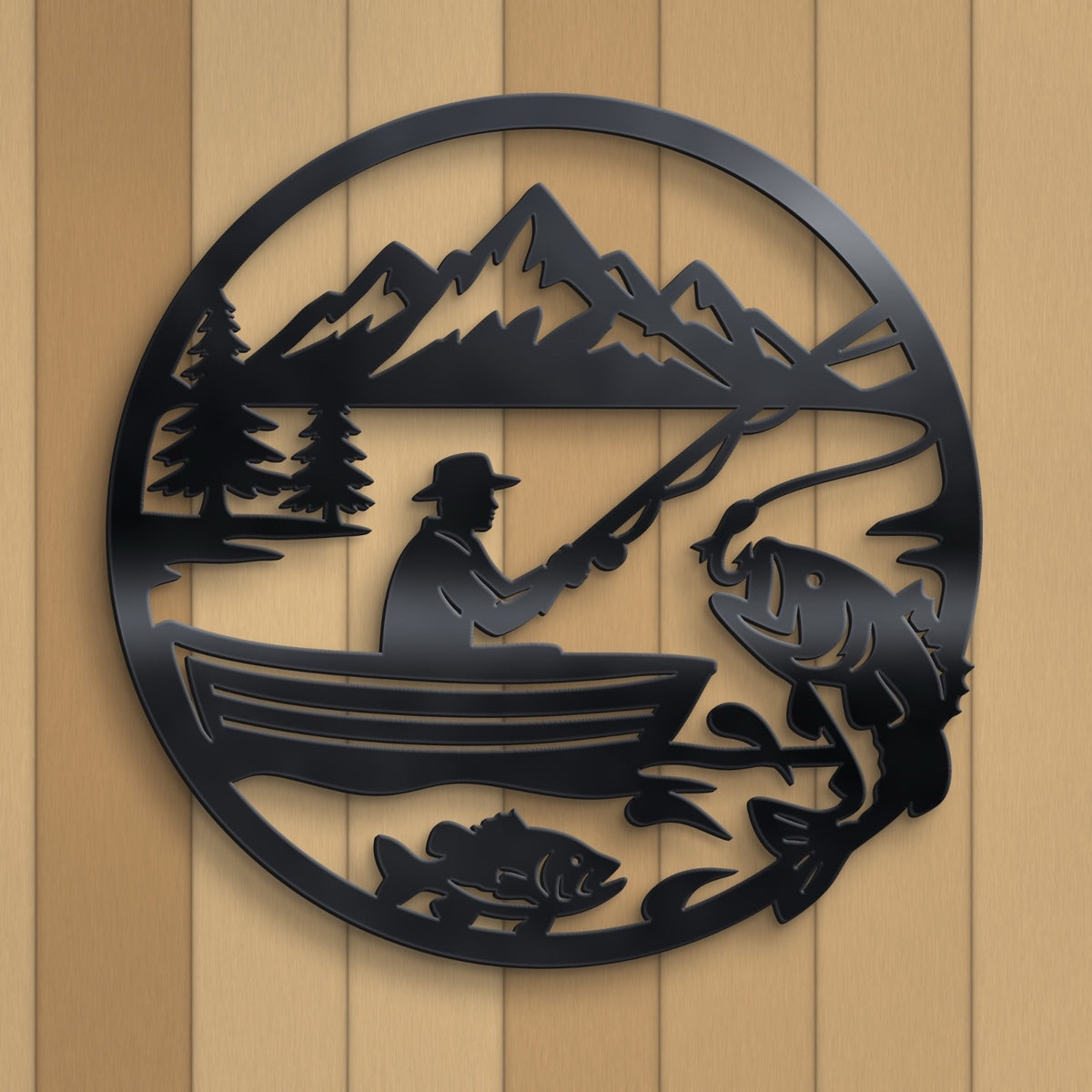 Black metal wall art featuring a circular fishing scene with a person in a boat, mountains, trees, and fish, mounted on a light wood plank background.