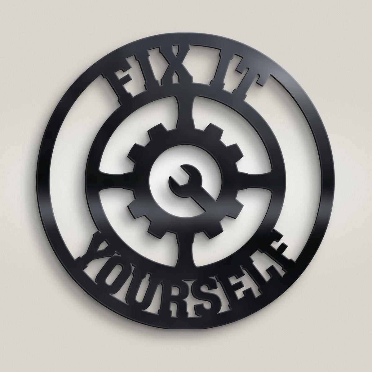 Black metal wall art featuring a circular design with a central gear and wrench motif, surrounded by the words 'FIX IT YOURSELF' in cutout lettering, displayed against a white background.